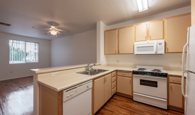  an empty kitchen with white appliances and wooden cabinets
